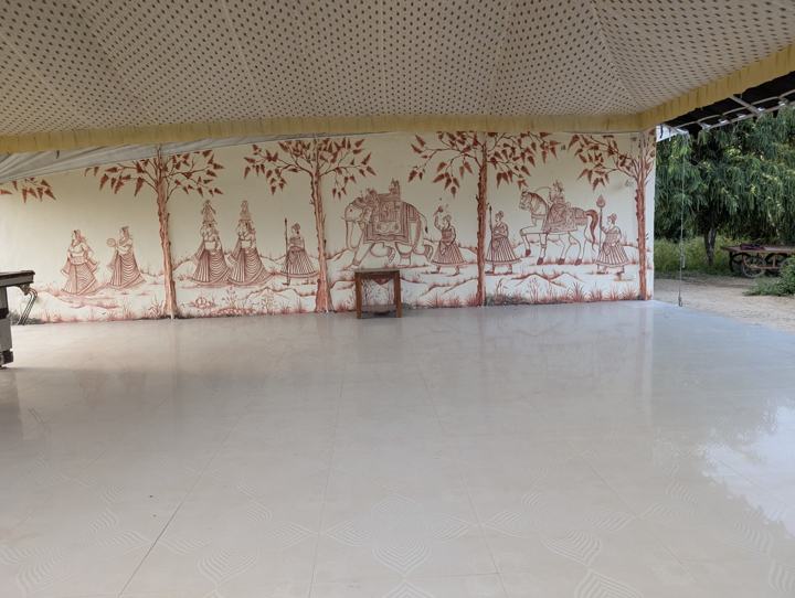 A long wall painted with Rajasthani scenes of riders, elephants and trees