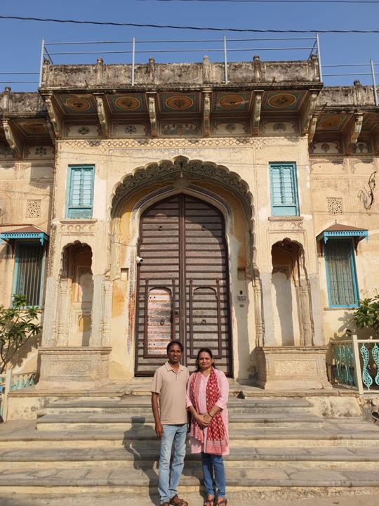 Two travellers at a carved stone haveli entrance